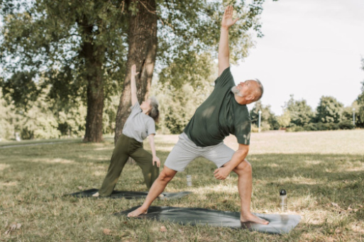 Ein alter Mann und ein alte Frau machen als Seniorensport Yoga im Park